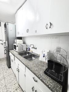 门多萨Hermoso, amplio y nuevo departamento, en la mejor ubicacion de la ciudad de Mendoza的厨房配有白色橱柜、水槽和微波炉
