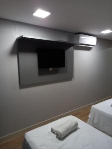 若昂佩索阿Manaíra Apart Hotel - 1606的带电视的墙壁和床上的2条毛巾