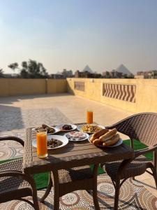 开罗Four pyramids Guest house pyramids View的露台上的桌子上摆放着食物和饮料