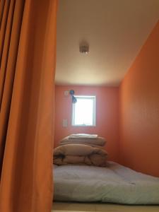 神户格拉格拉宾馆的一间卧室设有橙色的墙壁和一张带窗户的床