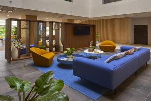 坎昆City Express Plus by Marriott Cancun Aeropuerto Riviera的客厅配有蓝色的沙发和黄色的椅子