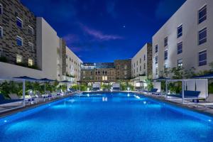 坎昆City Express Plus by Marriott Cancun Aeropuerto Riviera的一座大型游泳池,在晚上在建筑前