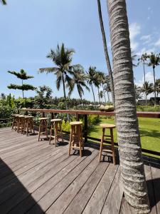 BalianDesa Cabins的一个带凳子和棕榈树的木甲板