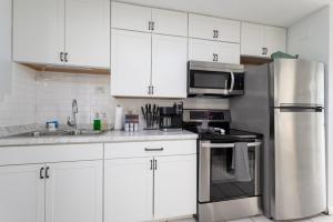 杰克逊维尔海滩Be A Nomad Beachside Apartments的厨房配有白色橱柜和不锈钢冰箱