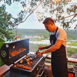 Chomka Thnong Resort的一个人在烧烤架上做饭