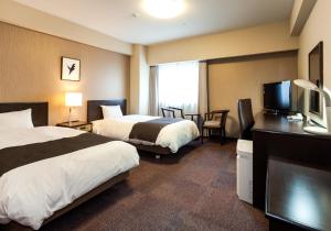 水户茨城水户大和ROYNET酒店(Daiwa Roynet Hotel Ibaraki Mito)的酒店客房设有两张床和一台平面电视。