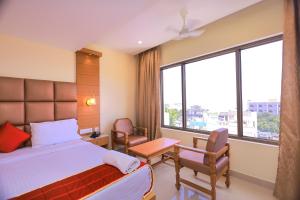 根尼亚古马里Hotel Sangam的一间卧室配有床和椅子以及大窗户