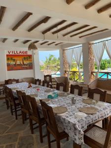 马林迪Coral Village的大型用餐室配有大桌子和椅子