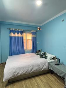 加德满都Sagarmatha View Homes的一间卧室配有一张蓝色墙壁的床和一扇窗户