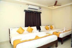 斯里卡拉哈斯蒂Hotel Elite Inn的客房配有两张带橙色和白色枕头的床。