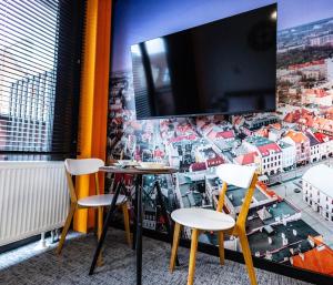 格利维采Apartamenty Plebańska-Rynek的一间设有两把椅子和一台墙上的电视的房间