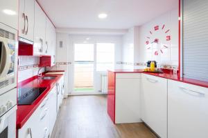 阿罗约德莱恩科缅达Apartamentos GO - Arroyo Ático Regato A- 62 Salida 130的厨房配有白色橱柜和红色台面