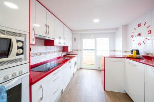 阿罗约德莱恩科缅达Apartamentos GO - Arroyo Ático Regato A- 62 Salida 130的厨房配有白色橱柜和红色台面
