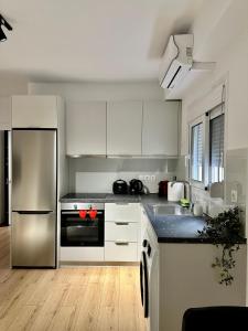 帕特雷City Centre Apartment的厨房配有白色橱柜和不锈钢冰箱