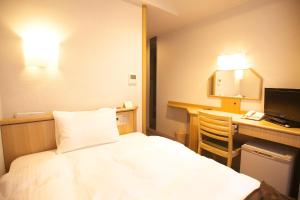 横手市Yokote Plaza Hotel的配有一张床和一张书桌的酒店客房