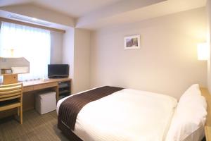 横手市Yokote Plaza Hotel的酒店客房配有一张床和一张带电脑的书桌