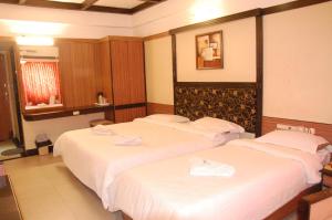 哥印拜陀Hotel Blue Star的配有白色床单的酒店客房内的两张床