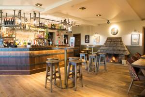 EatonWaggon and Horses, Eaton, Congleton的酒吧设有凳子,餐厅设有壁炉