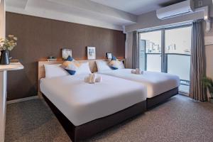 大阪Apartment Hotel 11 Shinsaibashi III的配有大窗户的酒店客房内的两张床