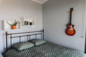 ParekklishaZima Edge的卧室配有一张壁挂吉他的床