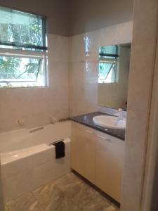 伯诺尼Blue Oasis Apartments的浴室配有盥洗盆、浴缸和镜子