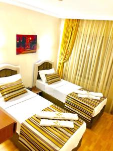 伊斯坦布尔MARDİA CİTY OTEL的配有黄色窗帘的酒店客房的两张床