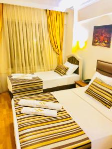 伊斯坦布尔MARDİA CİTY OTEL的配有黄色窗帘的酒店客房的两张床