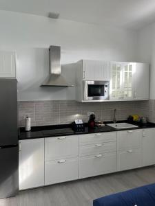 阿古洛Meriga的厨房配有白色橱柜和黑色冰箱。