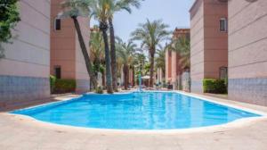 马拉喀什Riad Nezha的一座棕榈树游泳池和一座建筑