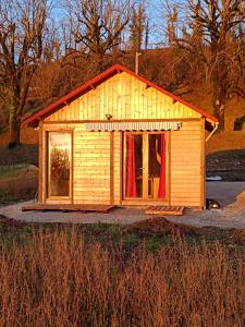 Ménétrux-en-JouxLa p'tite maison bois du hérisson的一座带红色窗帘的小木房子