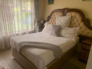 哈拉雷The Crown Inn Guest House的卧室配有一张带白色床单和枕头的大床。