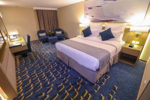 欧奈宰فندق شيرفل الواحة عنيزة Cheerful Al Waha Unayzah Hotel的酒店客房带一张大床和一把椅子