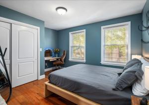 Mount VernonColorful, Comfy & Modern - Close to NYC - Parking!的一间卧室设有蓝色的墙壁、一张床和一张书桌