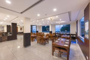 达兰萨拉Stone Wood Mountain Resort, Dharamshala的餐厅设有木桌、椅子和窗户。