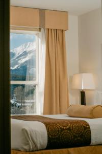 戈尔登Ramada Golden的一间卧室设有窗户,有雪覆盖的山
