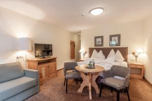 索尔登Hotel Hubertus inklusive Summercard的酒店客房带一张床、一张桌子和椅子