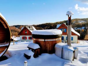 普热谢卡Kolorowe Karkonosze的雪覆盖的木桶,有房子的背景
