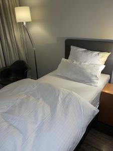 埃尔克伦茨林登霍夫酒店的一张带白色床单的床、一盏灯和一把椅子
