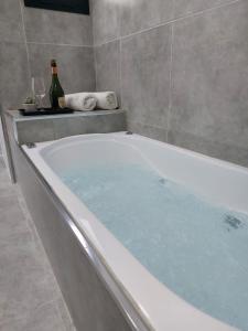 巴拉德罗APART HOTEL RIBERA DEL BARADERO pileta climatizada的浴缸配有两瓶葡萄酒和两杯酒