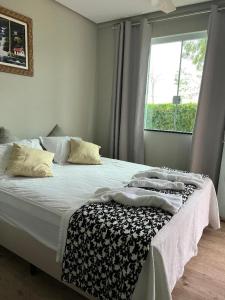 卡皮托利乌Cantinho da Alegria Suítes的一间卧室配有一张带白色床单的床和一扇窗户。