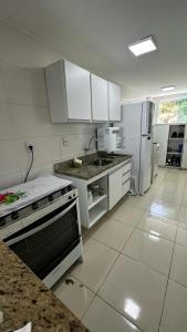 伊列乌斯Apt. em Praia do Sul de Ilhéus的厨房配有白色橱柜、炉灶和冰箱。