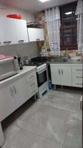 加罗帕巴Casa de 3 Quartos em Garopaba - Bairro Ferraz的厨房配有白色橱柜和炉灶。