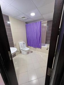 迪拜Peaceful Partition Room Near Mall of the Emirates的浴室配有卫生间和紫色的浴帘
