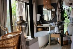 侯斯普瑞特African Flair Boutique Safari Lodge的一间带浴缸和大镜子的浴室