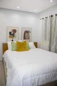 圣多明各Casa de Nini的一张配有白色床单和黄色枕头的大床