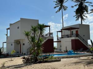 Tha SalaChansi Beachresort的海滩上的房子,带有游泳池和棕榈树