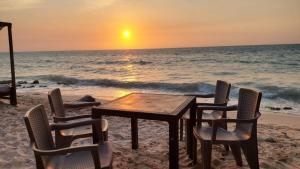 卡塔赫纳Hugos Place Baru的海滩上的桌椅和日落