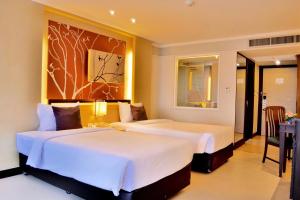 董里Rua Rasada Hotel - The Ideal Venue for Meetings & Events的酒店客房设有两张床和一张桌子。