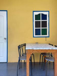 格兰岛The kn kohlarn resort的一张桌子和椅子,靠着黄色的墙壁,窗户