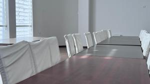 乌尔根奇Parvoz Hotel的一间会议室,配有长桌和白色椅子